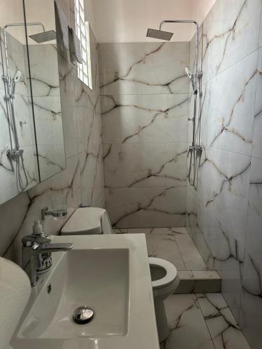 a white bathroom with a sink and a toilet at Chateau de Mankosah in Accra