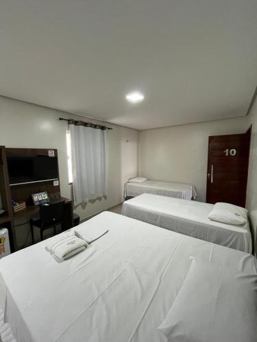 ein Hotelzimmer mit zwei Betten und einem Schreibtisch in der Unterkunft Seller Hotel in Sobral