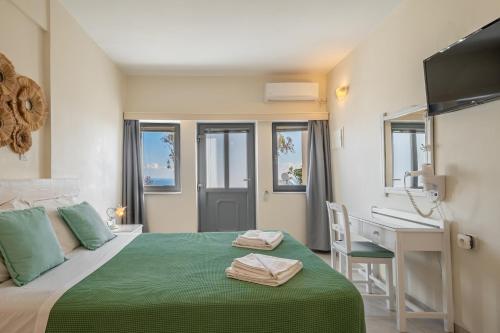 a hotel room with a bed and a desk and a sink at Ersi Villas in Firostefani