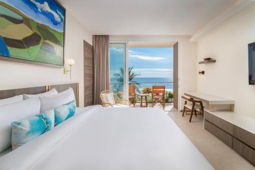 a bedroom with a bed and a desk with a view at Clarita's Beach Bar & Resort, WorldHotels Elite in Jacó