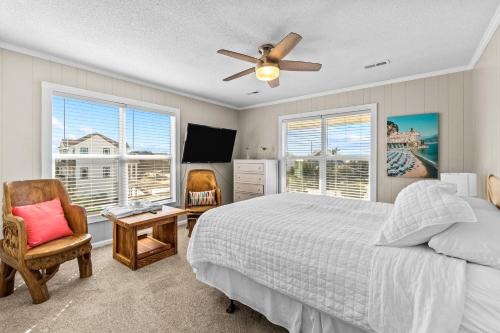 a bedroom with a bed and a tv and two windows at Beachfront Villa Royale OBX in Avon