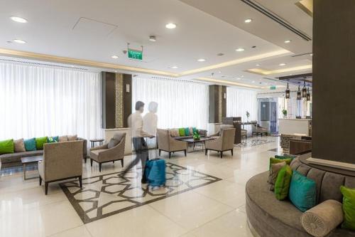 two people standing in a lobby with chairs and tables at Taba Al Salam in Medina
