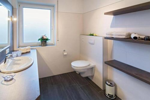 a bathroom with a toilet and a sink and a window at Tillmanns Stadtlounge in Norden