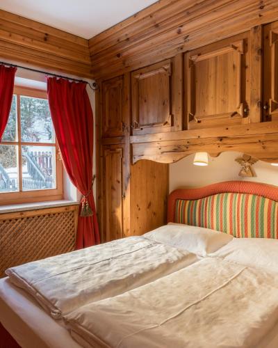a bedroom with a bed with wooden walls and a window at PLOSE Parkhotel & Residence in Bressanone