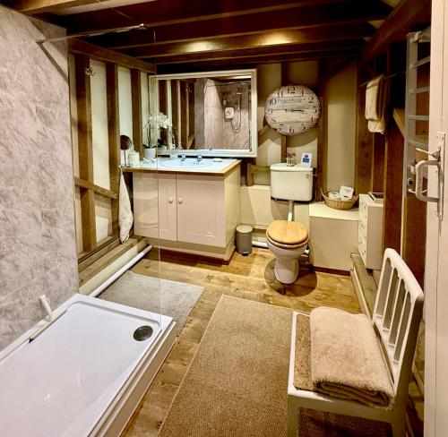 a bathroom with a tub and a toilet and a sink at Luxurious Country Barn in Baughurst
