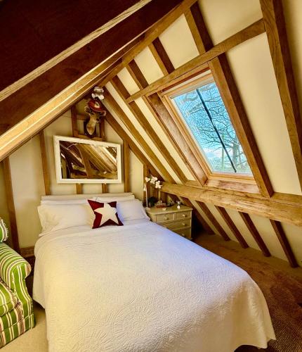a bedroom with a white bed in an attic at Luxurious Country Barn in Baughurst