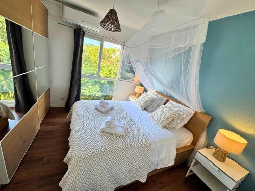 a bedroom with a white bed with a canopy at Horizon Doré Appt avec piscine - vue sur mer in Gourbeyre