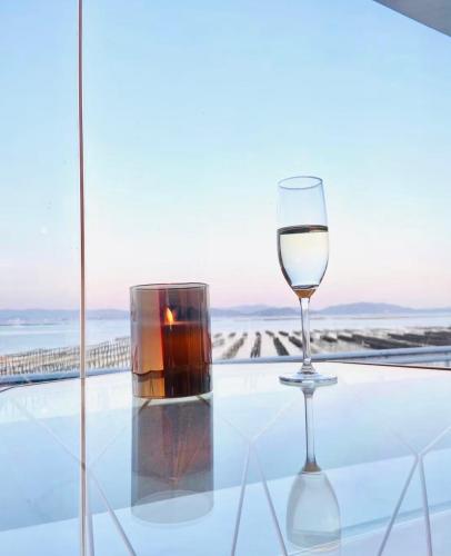 a glass of wine and a candle on a glass table at Mare di Miyajima マーレ ディ ミヤジマ in Miyajima