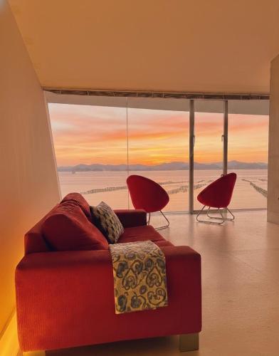 a living room with a red couch and a large window at Mare di Miyajima マーレ ディ ミヤジマ in Miyajima