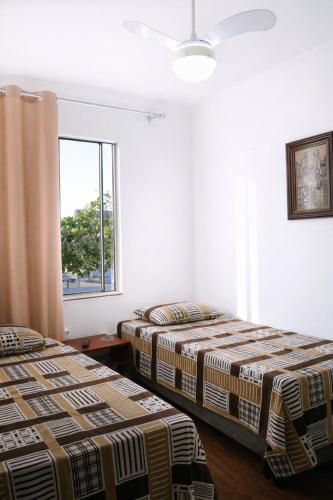 two beds in a room with a window at KOKIRA Apê in Campinas