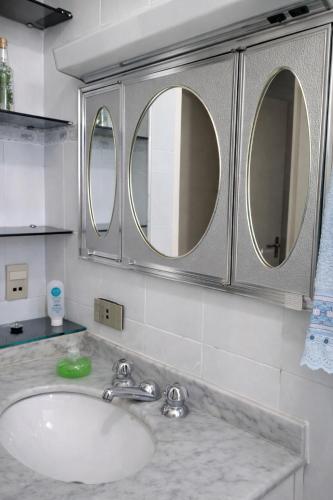 a bathroom with a sink and three mirrors at KOKIRA Apê in Campinas