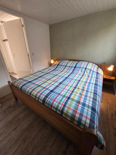 a bedroom with a bed with a plaid blanket on it at Hooisma's Erf in Kampen