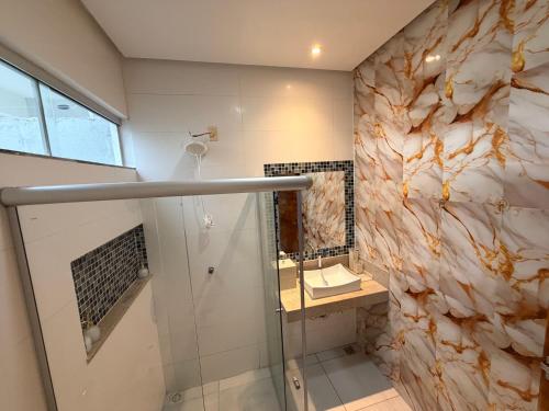 a bathroom with a shower and a stone wall at Casa com piscinas paragominas in Paragominas