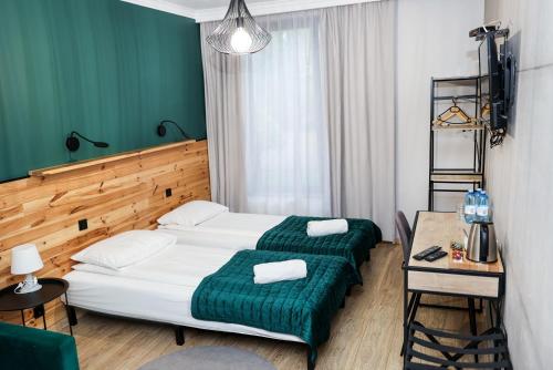 a bedroom with a bed with a green blanket and a table at Karczma Kujawska in Inowrocław