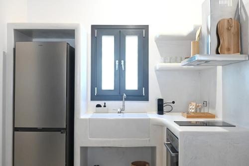 a white kitchen with a sink and a refrigerator at Alkyoni Celeste Kythnos in Kithnos