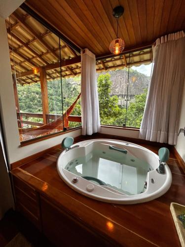 a large bath tub in a room with a window at Chalés Vale das Pedras in Venda Nova do Imigrante