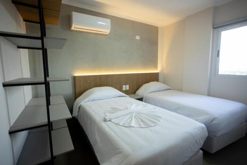 two beds in a small room with twoilit at Terraço Flat Hotel in Dourados