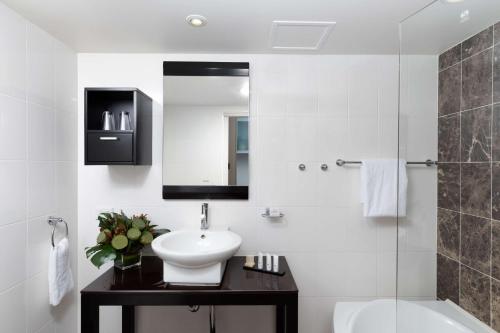 a white bathroom with a sink and a mirror at Rydges Mount Panorama Bathurst in Bathurst