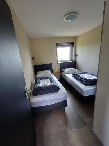 two beds in a room with a door open at Sunrise in Hollum