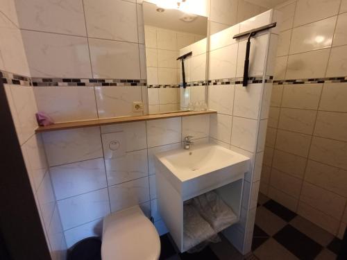 a white bathroom with a sink and a toilet at Sunrise in Hollum