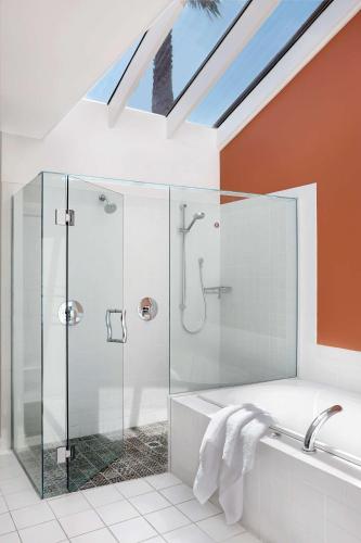 a glass shower in a bathroom with a skylight at Rydges Formosa Auckland Golf Resort in Auckland