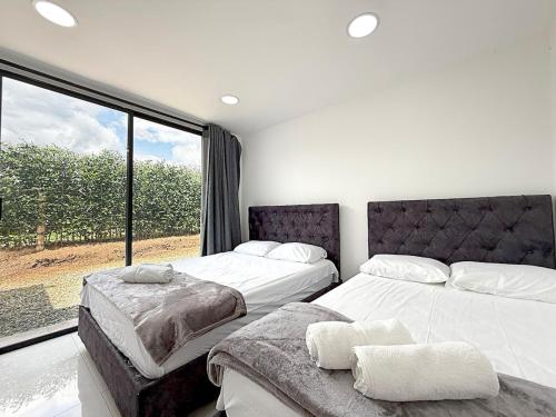 a bedroom with two beds and a large window at Villa adhara in Quimbaya