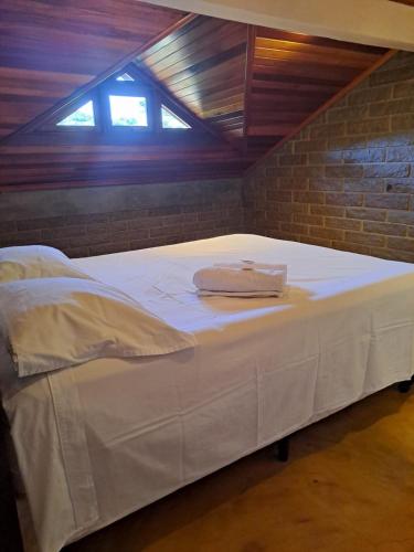 a large white bed in a room with a brick wall at Loft 73 in Bento Gonçalves