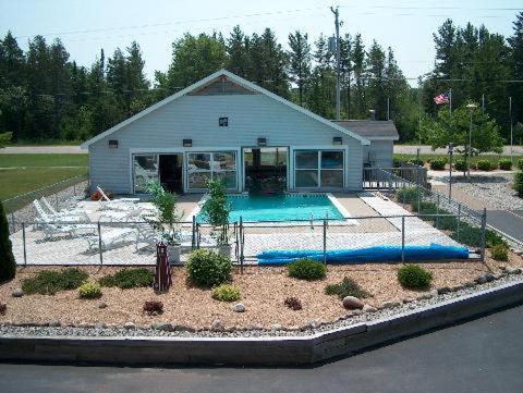 a house with a swimming pool in front of it at Sunrise Beach Motel in Mackinaw City