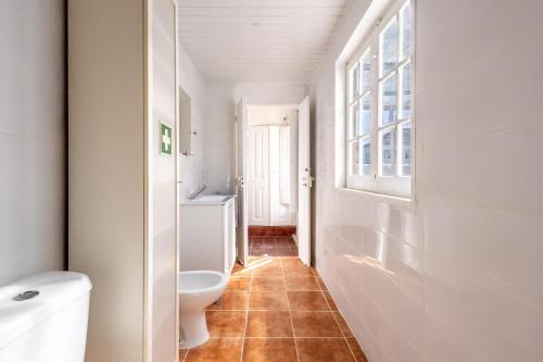 a bathroom with a toilet and a sink and a window at Salvaterra de Magos in Salvaterra de Magos