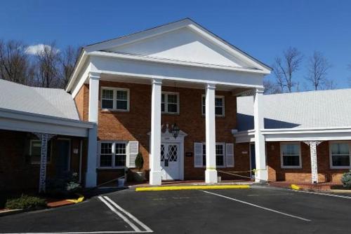 a red brick building with white columns at Governor House Inn Arlington/Falls Church in Falls Church