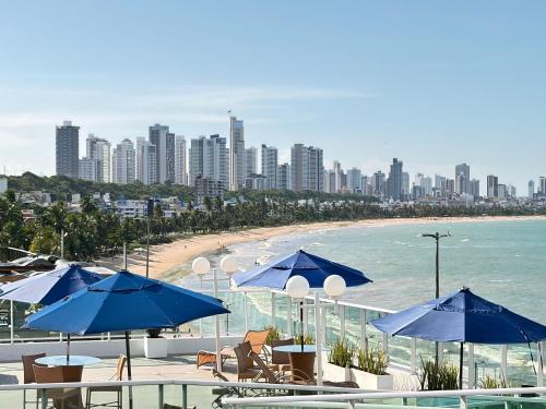 a view of a beach with blue umbrellas at Flat em Cabo Branco - Blue Sunset in João Pessoa