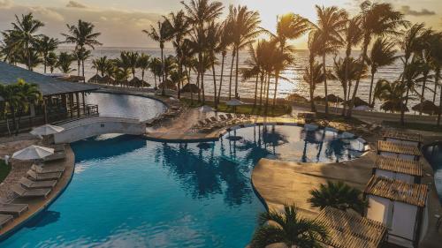 a resort swimming pool with palm trees and the ocean at Iberostar Selection Riviera Cancun - All Inclusive in Puerto Morelos