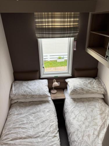 two beds in a small room with a window at Paws a while in Mainsriddle