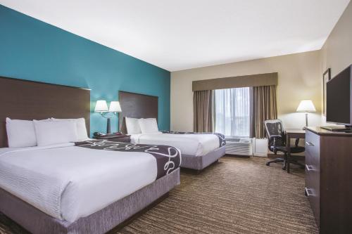 a hotel room with two beds and a desk at Comfort Inn & Suites Sarasota I75 in Sarasota