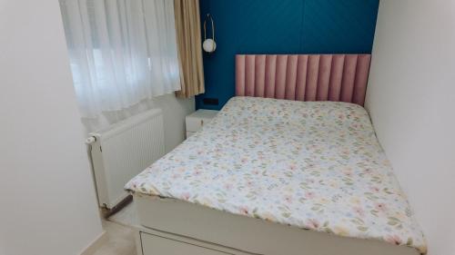 a small bedroom with a bed with a pink headboard at Lumina Residence Našice in Našice