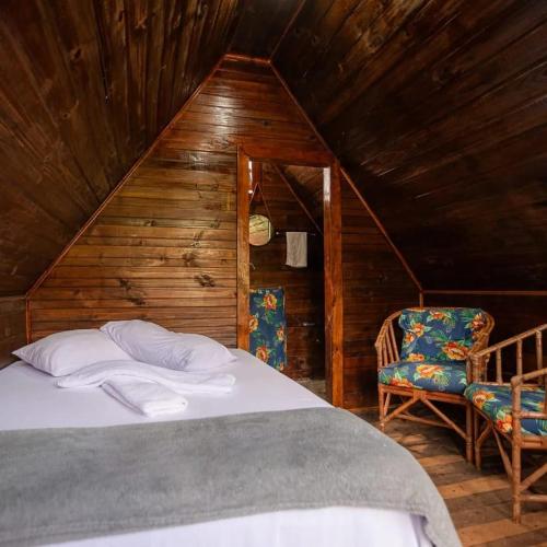 a bedroom with a bed and two chairs in a attic at Colinas do braga chalés in Brumadinho