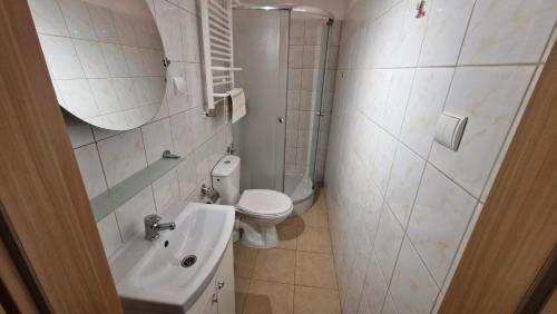 a white bathroom with a toilet and a sink at Villa Atol in Niechorze