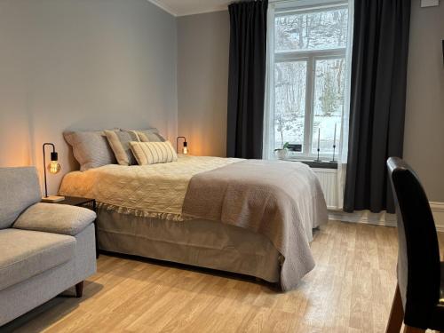 a bedroom with a bed and a couch and a window at Villa Bäckagård Bed and Breakfast in Åstorp