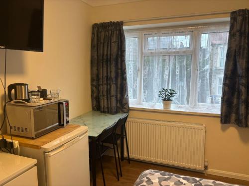 a kitchen with a small table and a window at Kensal Lodge Guest House in London