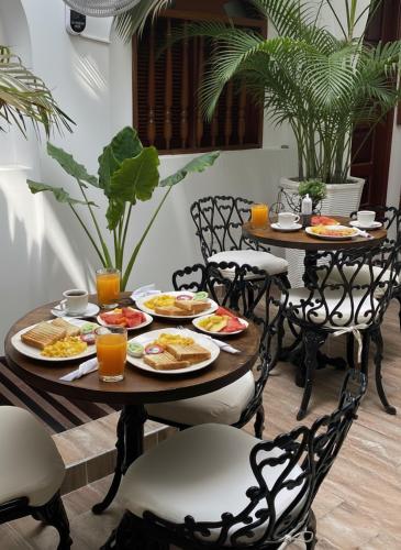a table with plates of food and orange juice at Hotel Casa Agustina in Cartagena de Indias