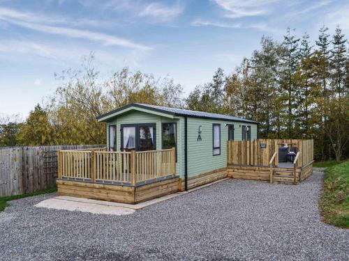a small green cabin with a wooden deck at Willow - Uk36374 in Westward