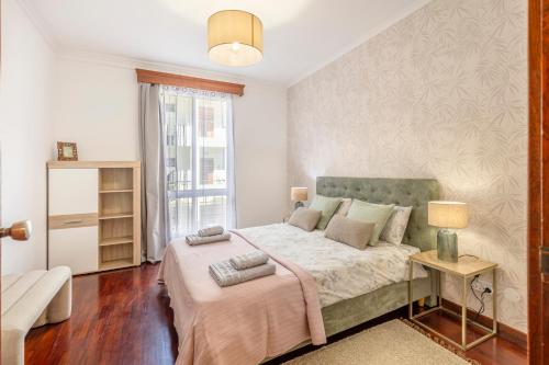 a bedroom with a large bed and a window at BoLina Caniço Center in Caniço