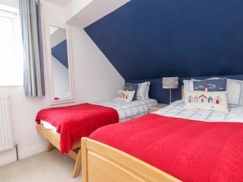 two beds in a bedroom with a blue wall at Fernlea in Morfa Nefyn