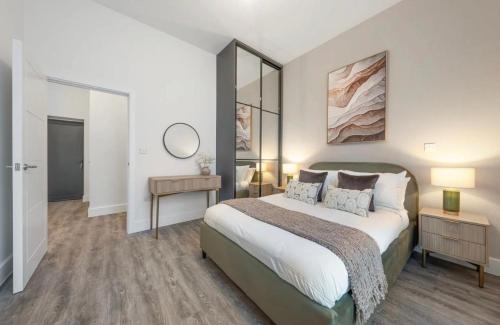 a bedroom with a large bed and a mirror at Stylish 2 Bedroom Flat Near City Airport - Pet Friendly, Free WiFi & Free Parking in London