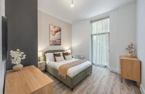 a bedroom with a bed and a table and a window at Stylish 2 Bedroom Flat Near City Airport - Pet Friendly, Free WiFi & Free Parking in London