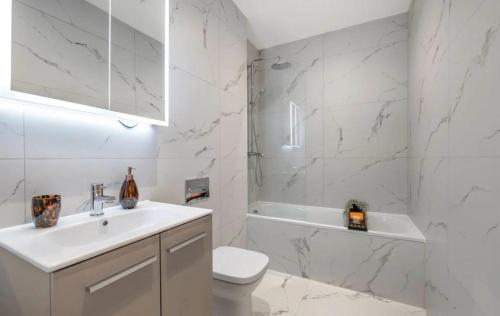 a white bathroom with a toilet and a sink at Stylish 2 Bedroom Flat Near City Airport - Pet Friendly, Free WiFi & Free Parking in London