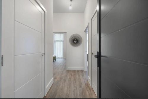 a hallway with white walls and a door and wood floors at Stylish 2 Bedroom Flat Near City Airport - Pet Friendly, Free WiFi & Free Parking in London