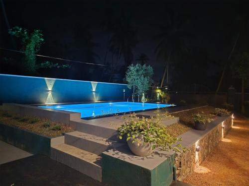 a swimming pool with lights in a backyard at night at Villa Erika in Induruwa