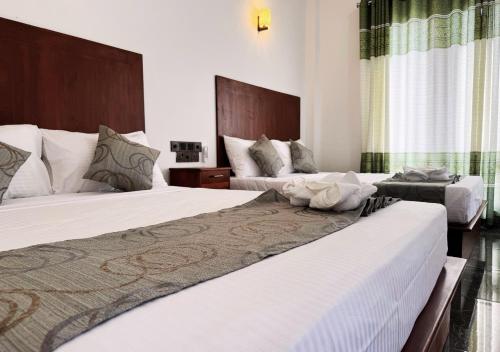 a hotel room with two beds with white sheets at Gagana Resort in Anuradhapura