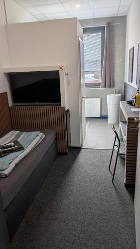 ein Schlafzimmer mit Bett und Schreibtisch sowie ein Badezimmer in der Unterkunft BUSINESS-MOTEL & XL-Parking, 24h-Checkin in Heimsheim